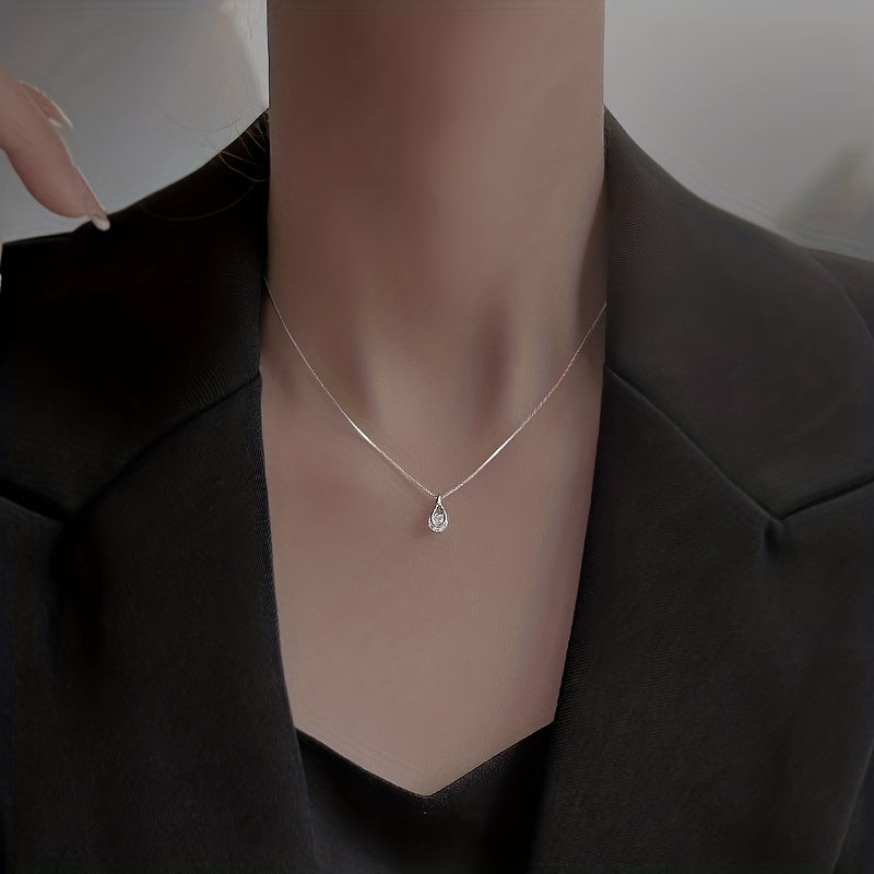 Dainty teardrop pendant worn at the collarbone