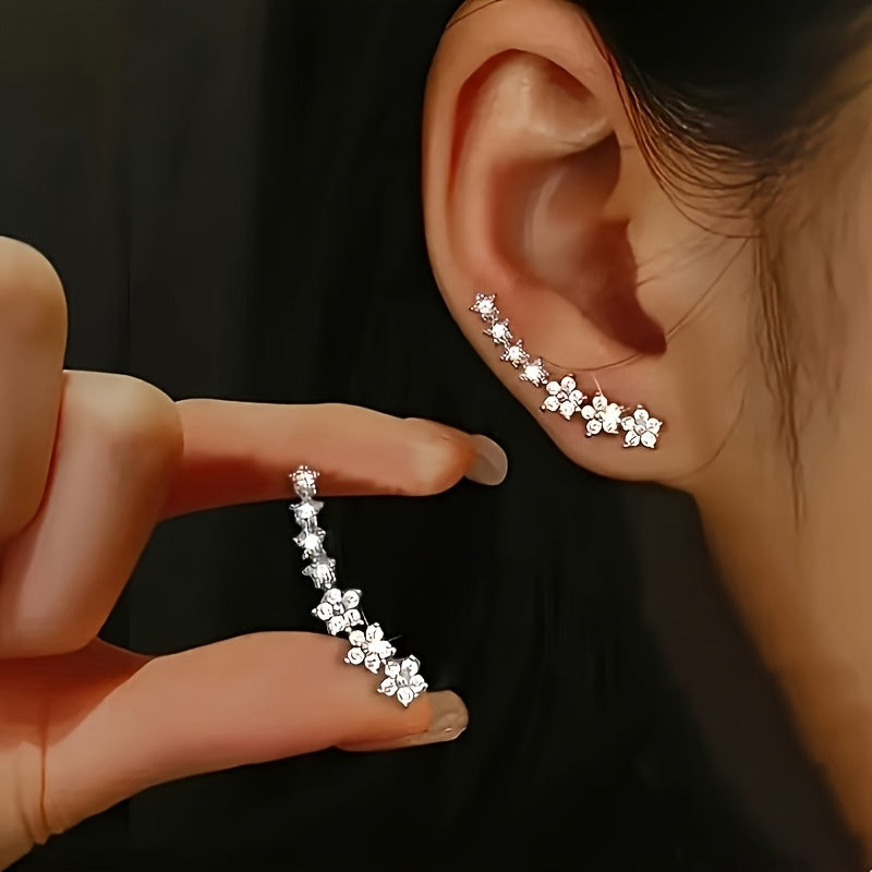 Astra star ear climber worn up the ear, with the second earring held in hand