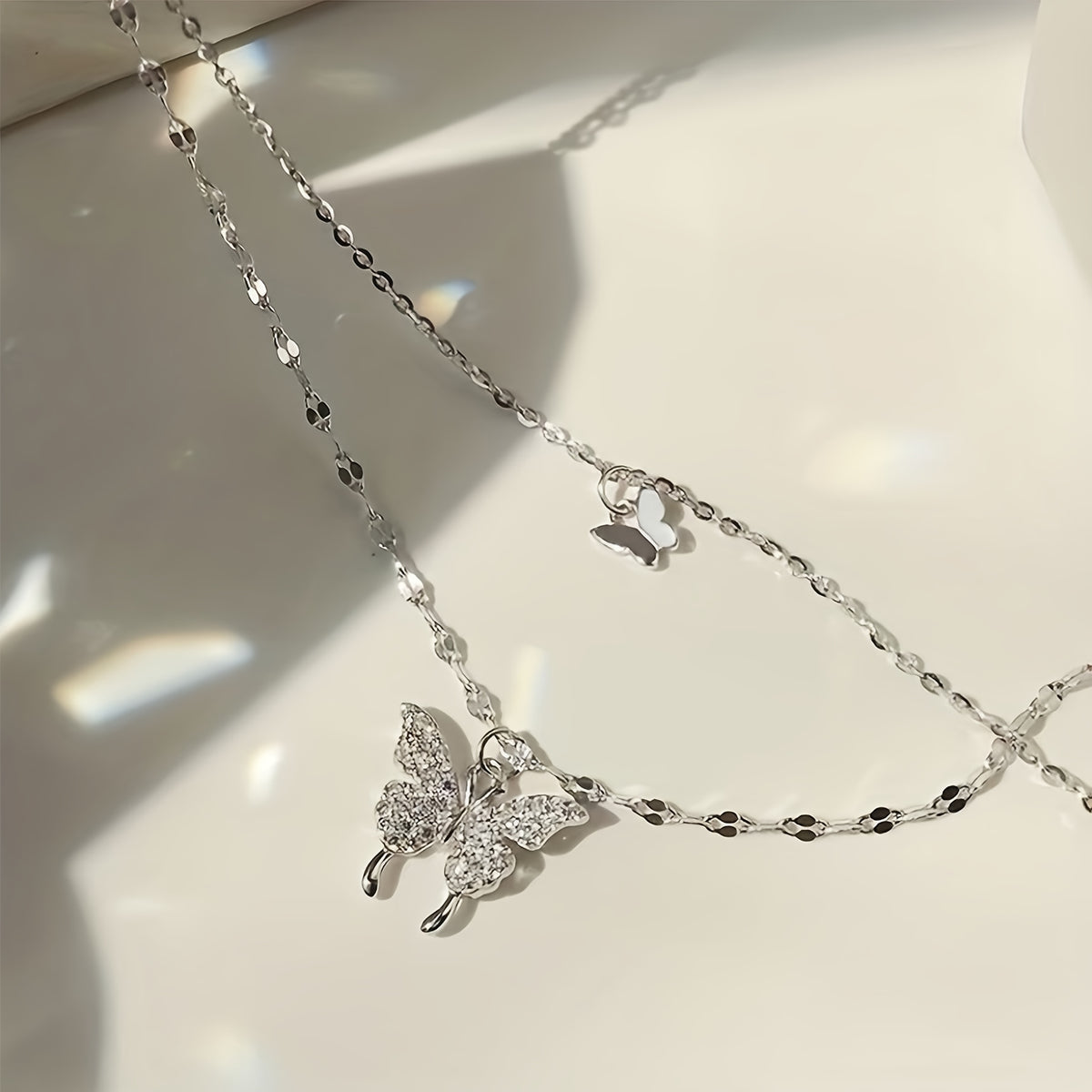 Papillon layered silver-tone chains with a pavé butterfly, side view