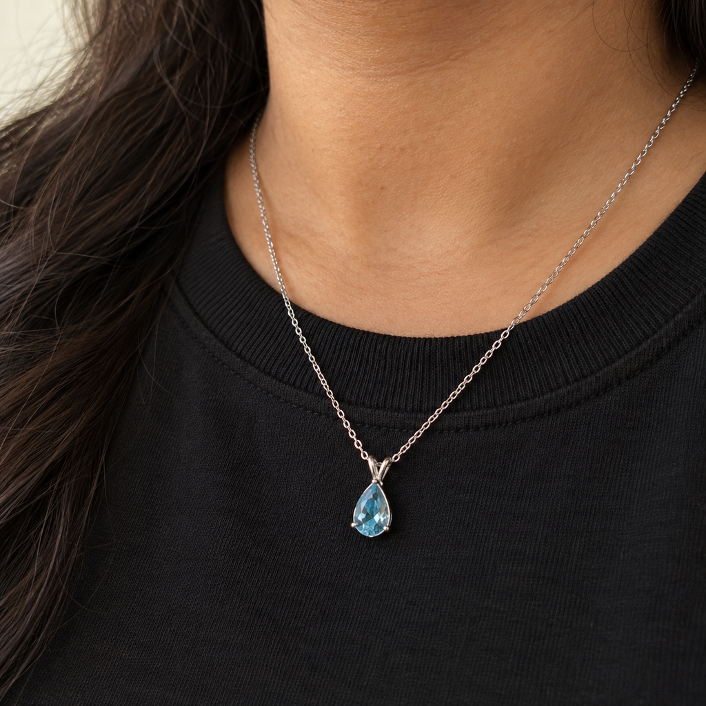 Sky-blue pear-cut pendant on a fine silver-tone chain – worn with a black crew-neck top