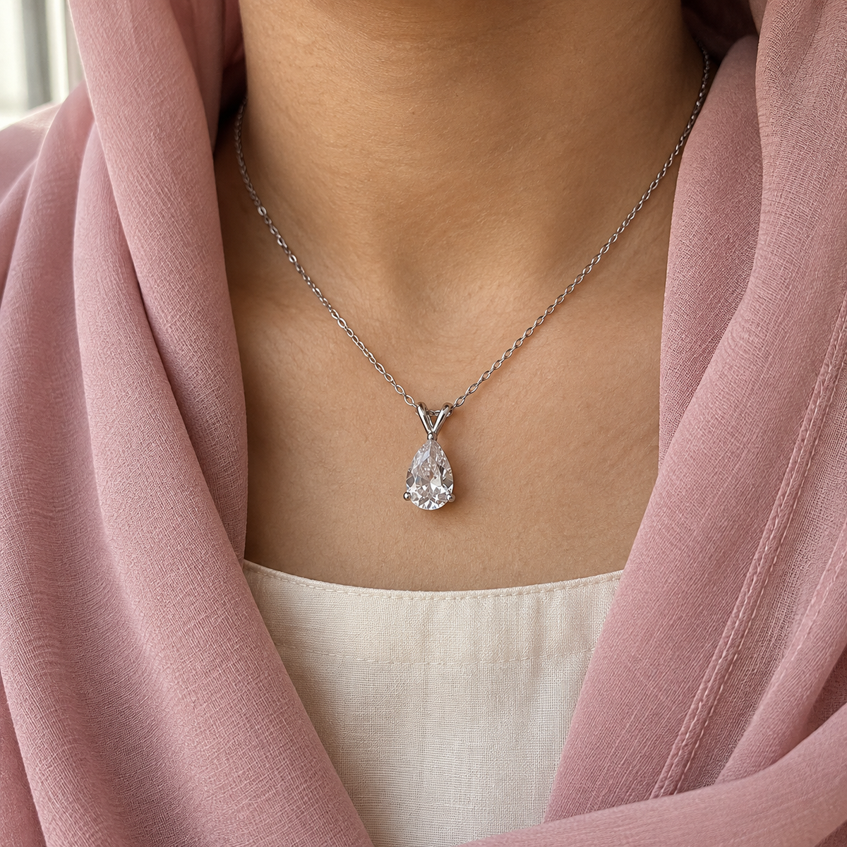 Clear pear-cut pendant on a fine silver-tone chain – worn with a dusty-pink dupatta framing the neck