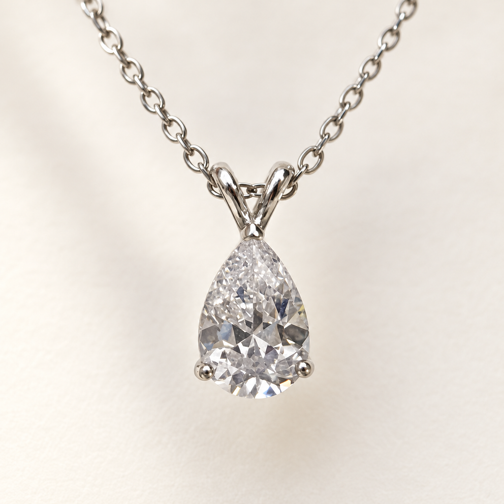 Clear pear-cut pendant on a fine silver-tone chain – macro of the stone and setting