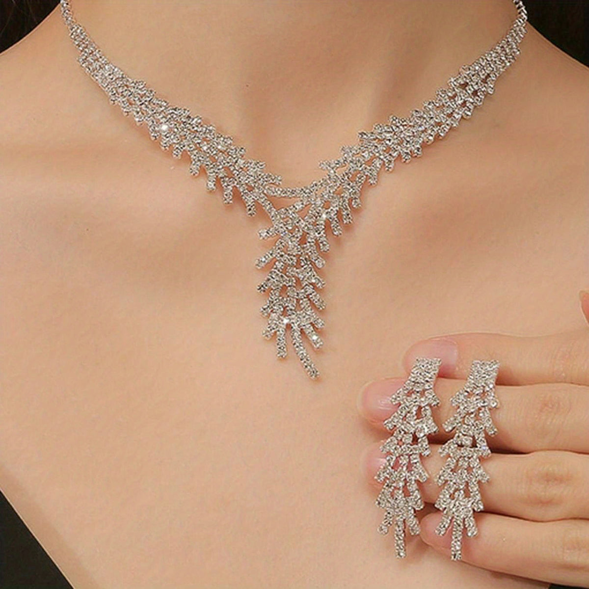 Aveline bridal crystal necklace worn with a matching earring held beside it
