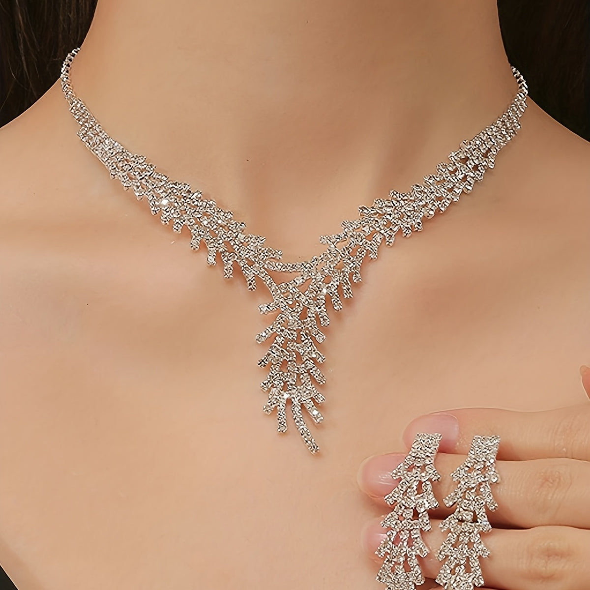 Aveline crystal necklace set worn on the collarbone, with the matching fringe earrings held in hand