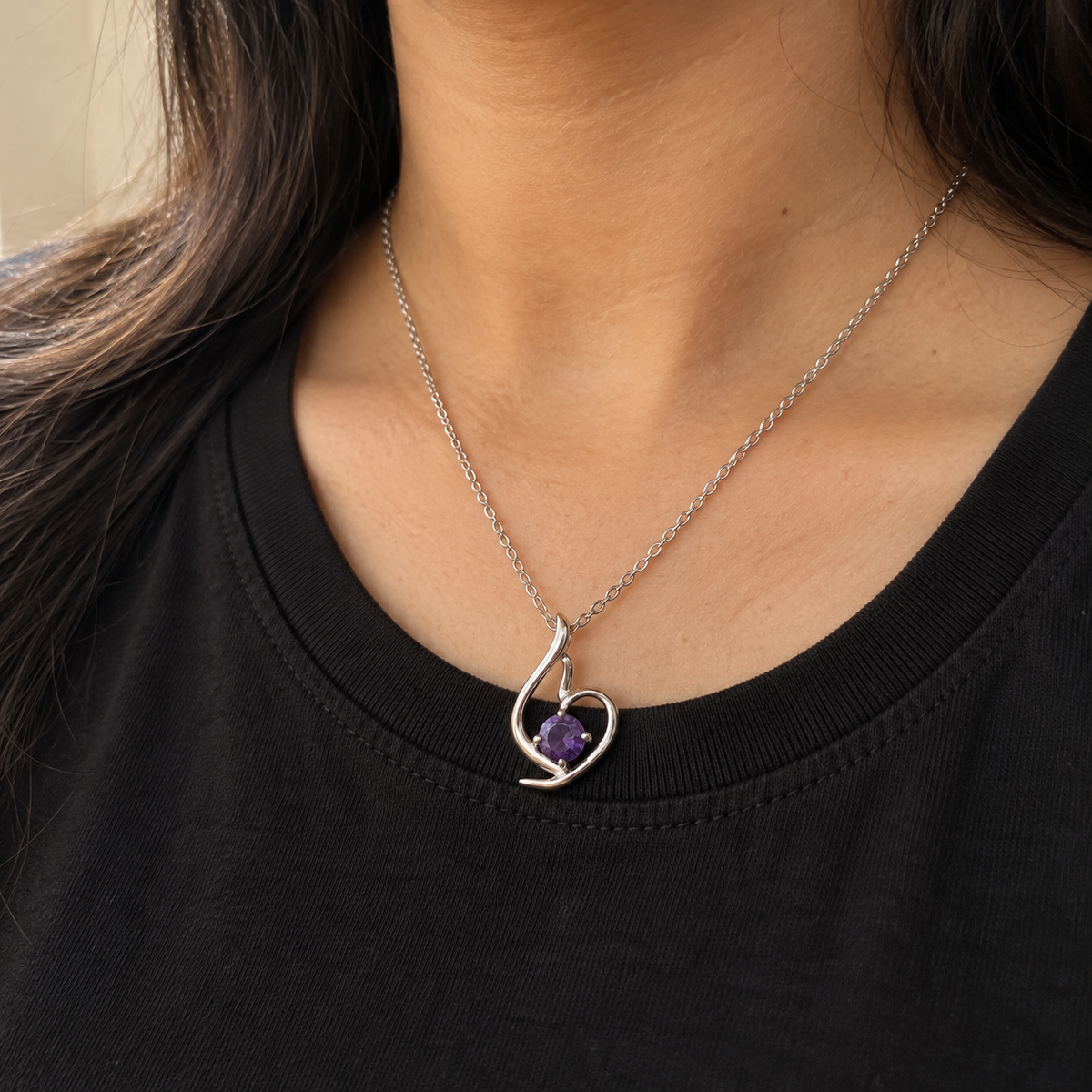 Lumière silver-tone heart pendant with a round violet stone – worn with a black crew-neck top