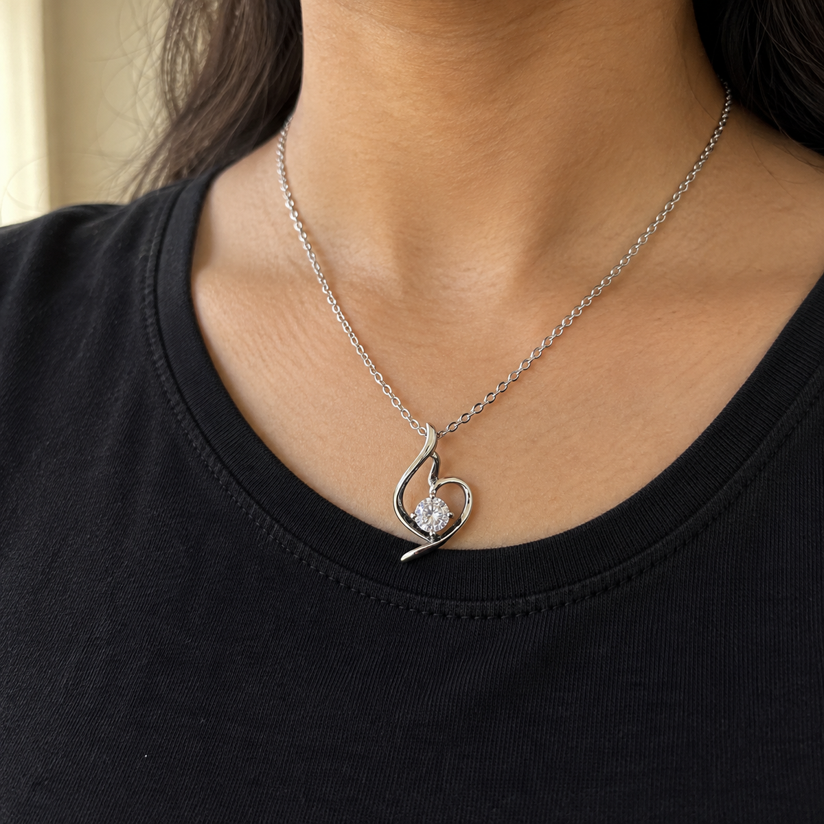 Lumière silver-tone heart pendant with a round clear stone – worn with a black crew-neck top