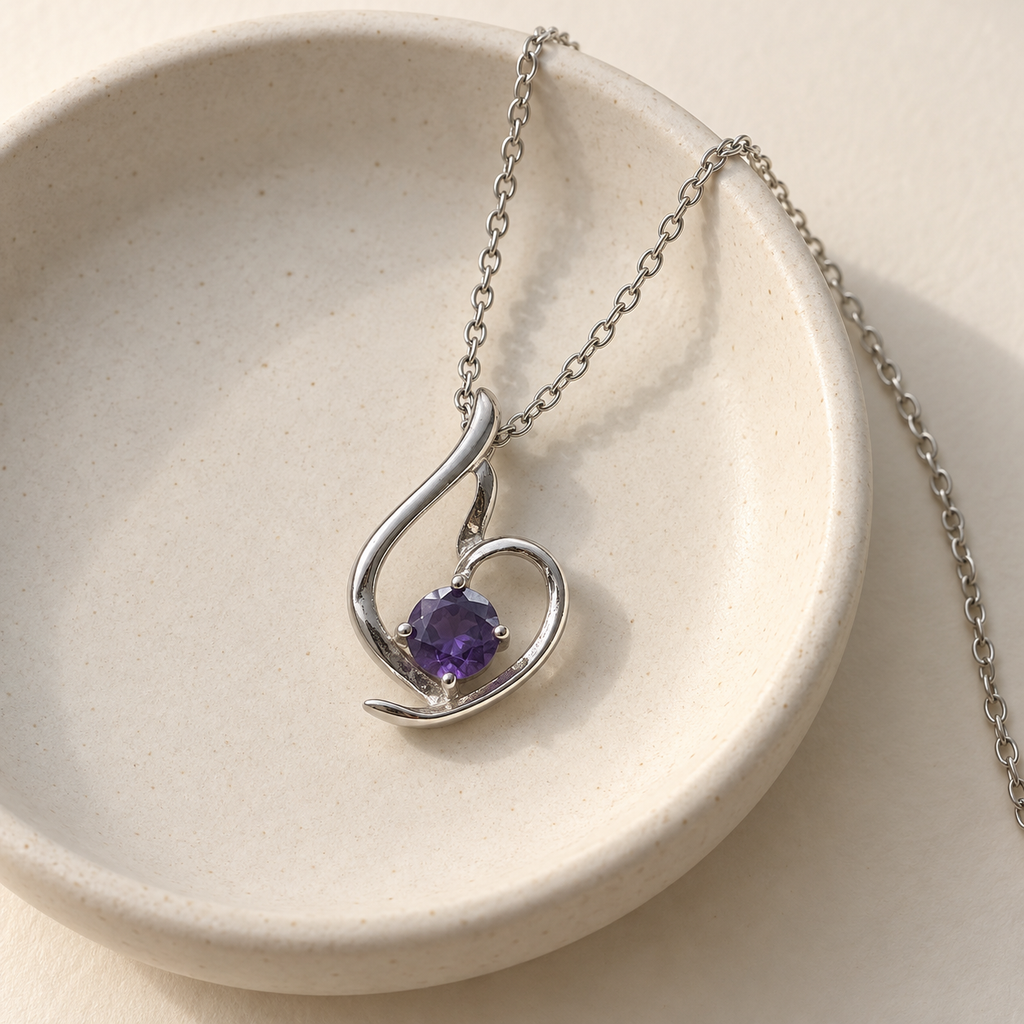 Lumière silver-tone heart pendant with a round violet stone – on a cream ceramic dish with the chain over the rim