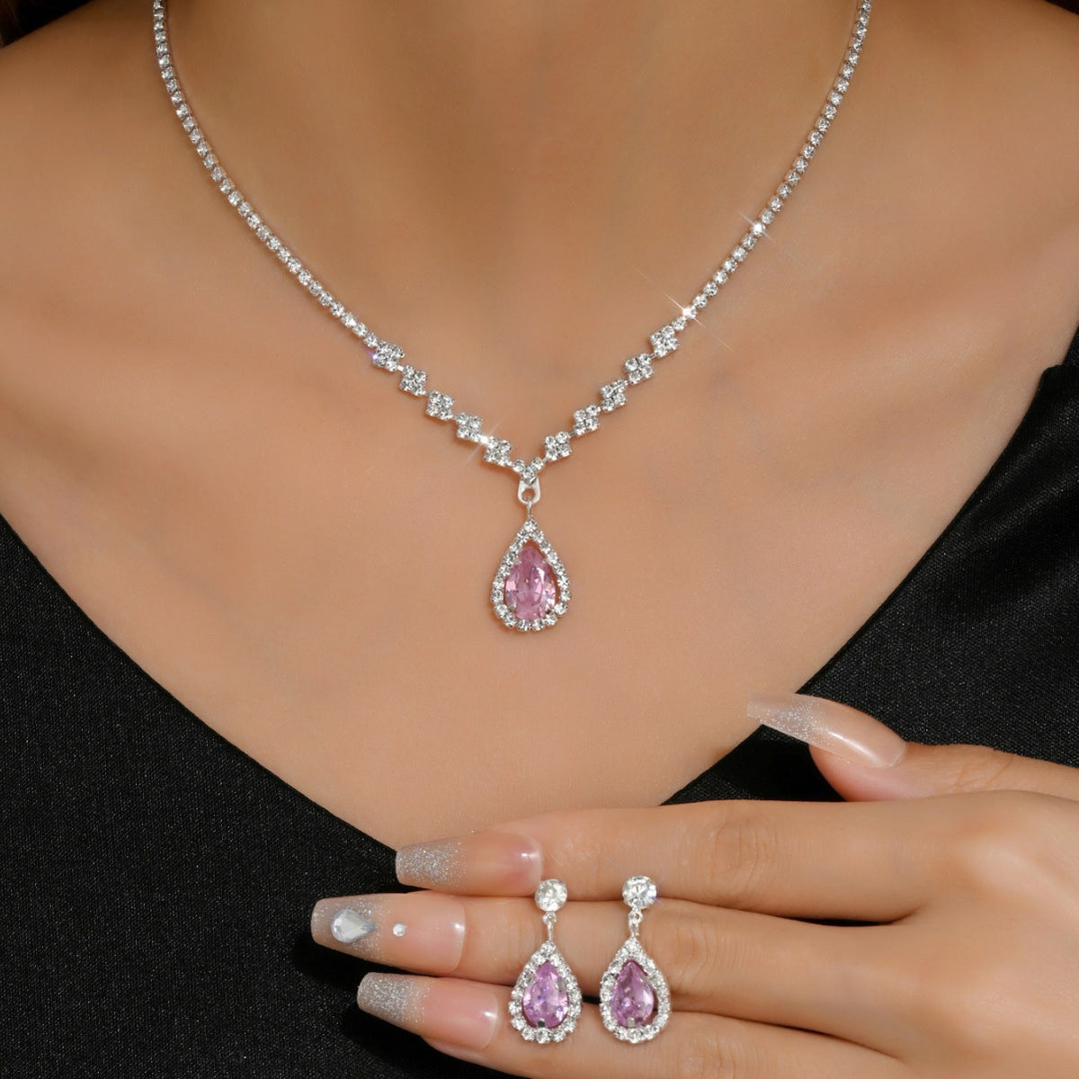 Soirée Drop Set in pink worn: teardrop necklace with matching earrings in hand