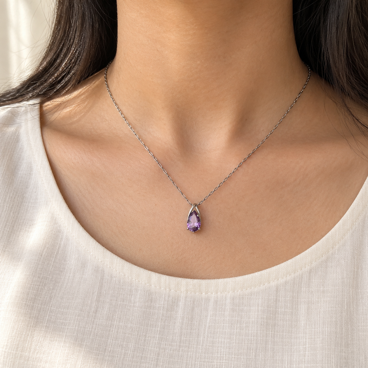 Purple pear-cut pendant on a fine silver-tone chain worn with an ivory kurta, collarbone view