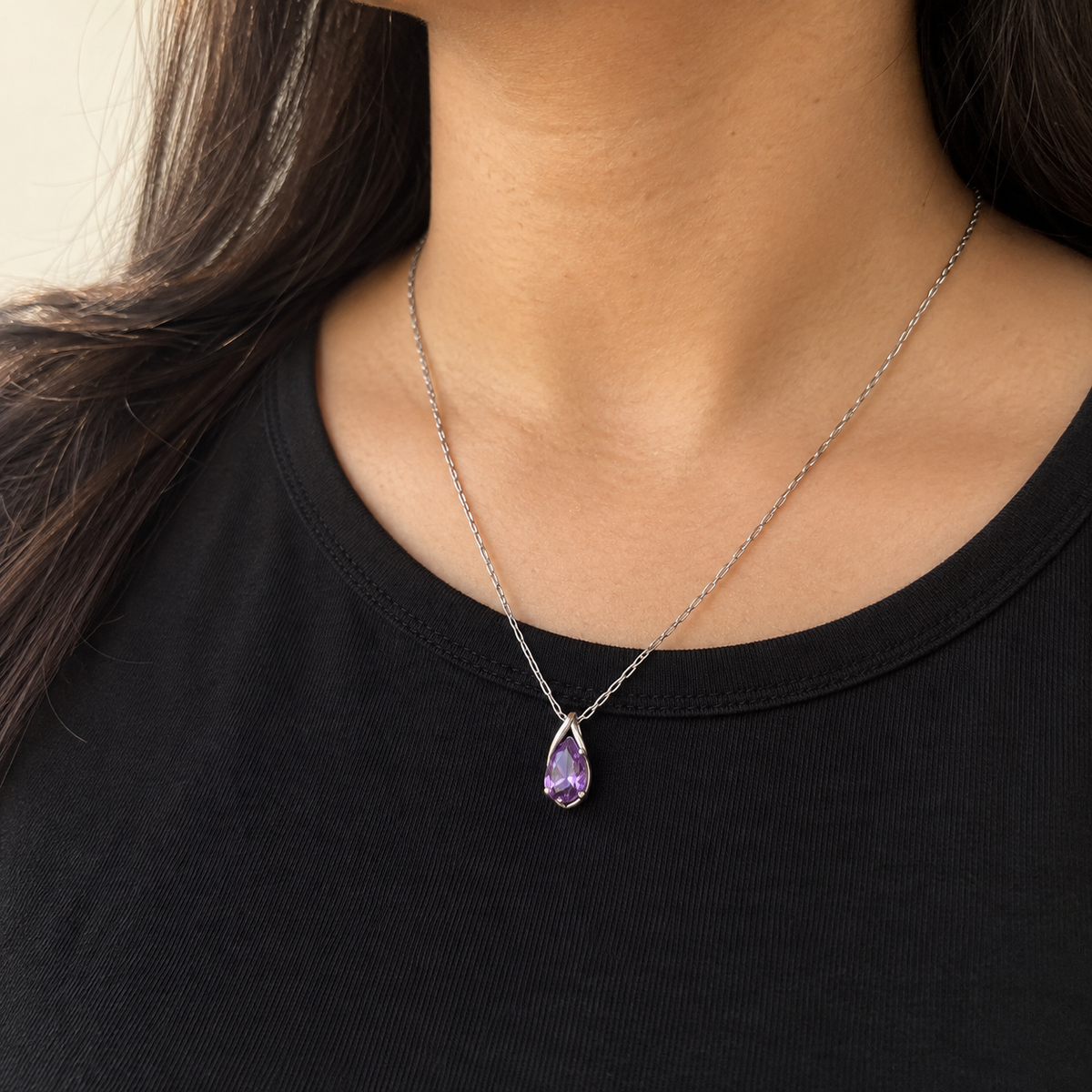Purple pear pendant necklace worn with a black crew-neck top